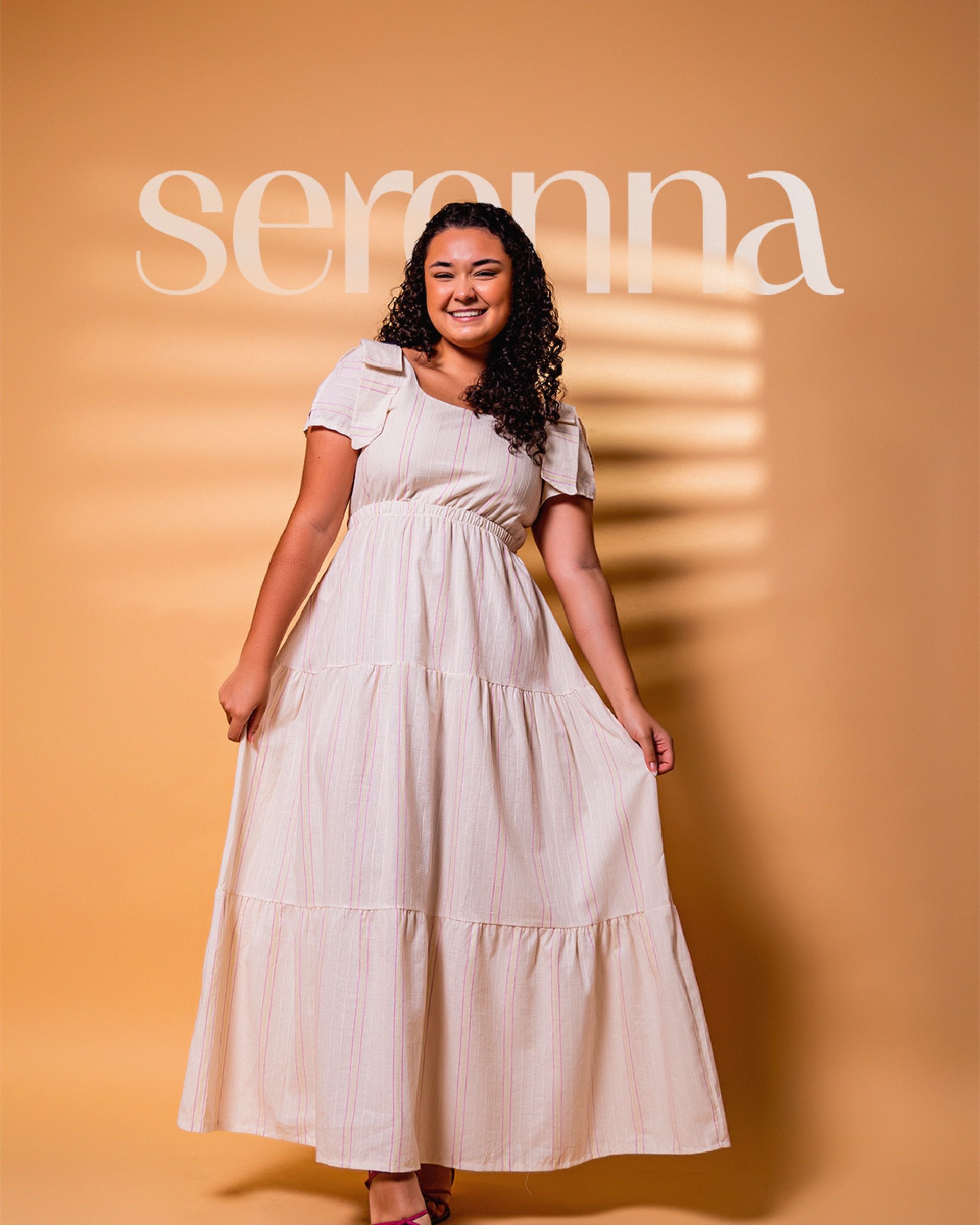 Modelo da Serenna de vestido claro com o logo ao fundo