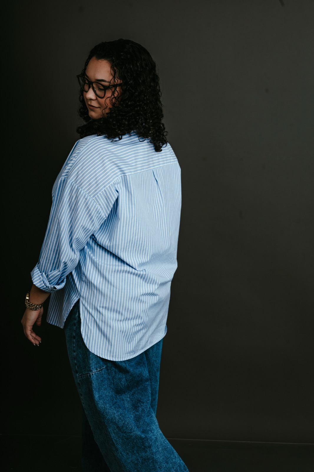 Retratada em movimento, camisa azul-clara, fundo escuro