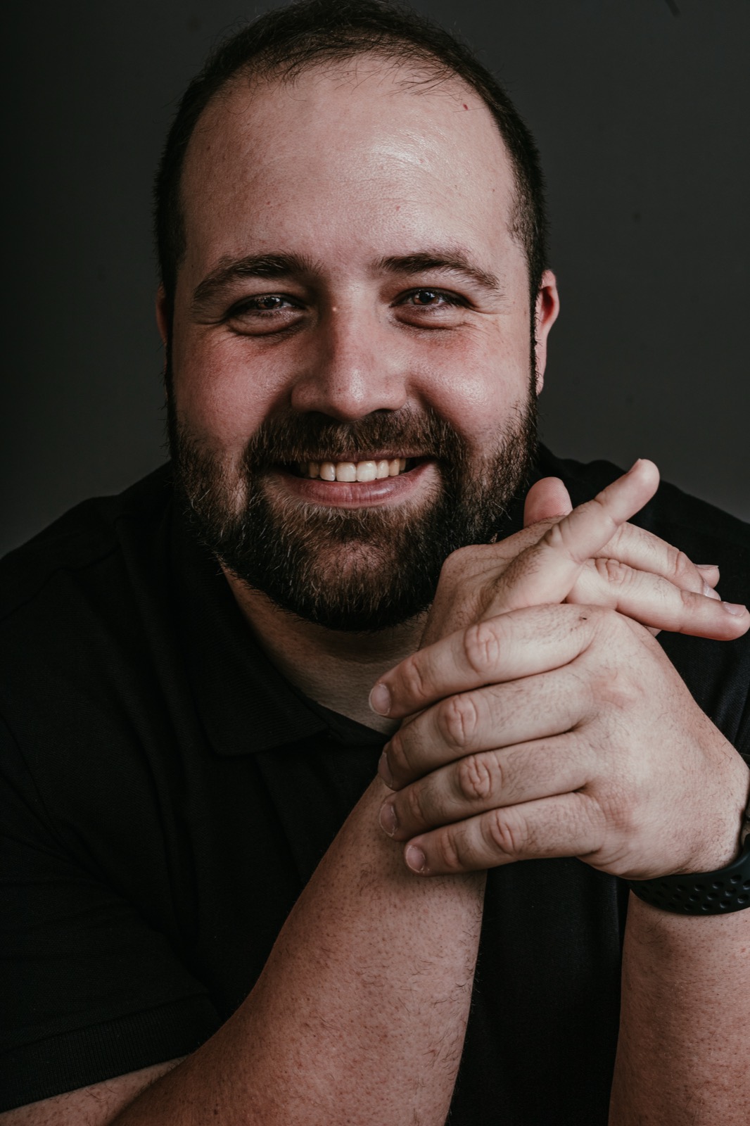 Retrato sorrindo, mãos entrelaçadas, fundo escuro